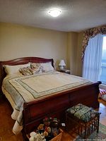 Full view of king size bed with floral quilted bedspread and cushions on the wooden bed frame.
