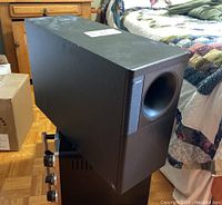 Side view of the Bose Acoustimass 10 Series II subwoofer showing black enclosure with slight dust and wear.