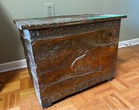 Full side angle view of the wood box showing the embossed brass nautical scene on the side panel and the carved edge of the box top.