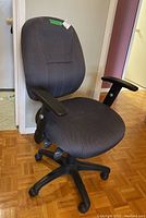Side angle view of gray cloth office chair showing seat, backrest, armrests, and five-legged caster base