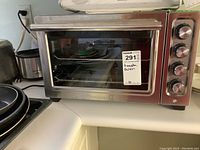 Full view of stainless steel KitchenAid counter oven on countertop showing glass door and control knobs.