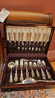 Open wooden box showing eleven Regency Plate dinner knives in upper rack and various serving pieces in lower tray.