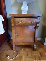 Front view of the wood end table showing drawer and door with decorative handles