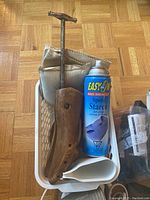 Wooden shoe stretcher with metal handle, Easy-Off Speed Starch spray can, and folded shoe care items in plastic basket