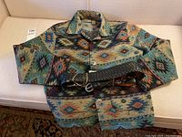 Full view of the Jane Ashley patterned jacket with the wide woven leather belt placed on top.