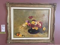 Full view of framed oil painting showing flowers in vase on board with ornate gilt frame.