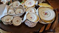 Overview of multiple plates, bowls, teacups and saucers inside padded fabric-lined storage cases on tabletop.