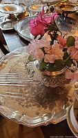 Various silver plated trays and serving pieces shown on a table, including large tray 21x14 inches and pedestal bowl with artificial flowers.