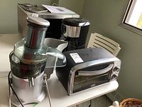 Photo of the Black and Decker coffee maker, Breville juicer, and Sunbeam toaster oven placed on a white table