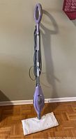 Full view of purple Shark Steam Mop with white mop pad attached and power cord wrapped around handle.