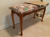 Wood framed bench with floral print seat cushion and beige runner laid across top