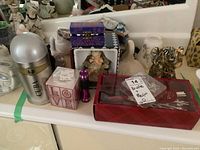Photo of multiple items including Cuba spray bottle, LOVE candle, purple flashlight, figurines, and red boxed hairbrush set