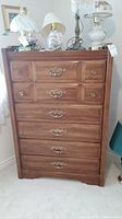 Front view of the wood dresser showing six drawers and brass handles with visible scratches.