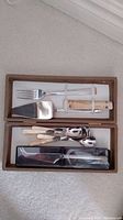 Photo showing cheese cutter, cake server and fork with 24k gold accent, along with coffee spoons packed in original boxes secured with elastic bands.