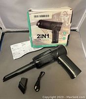Black 2-in-1 portable mini vacuum cleaner with a long narrow nozzle attached, a small brush attachment, USB charging cable, instruction sheet, and original box with some blemishes.