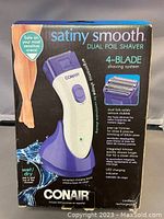 Front of retail box showing shaver image and key features: 4-blade shaving system, ergonomic shape, wet/dry use, cordless rechargeable, LED charging indicator.