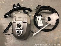 Top view showing main steamer unit with control knob, black hose with steam head, adjustable poles, and black Conair hanger.