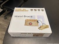 Closed box showing the product name 'Waist Brace' and a printed image of the beige belt with attached pump device.