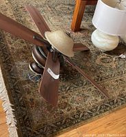 View showing full area rug with Bakhtiari pattern in green, rust and red colors, topped with a ceiling fan and lamp (not included). Rug pad underneath also visible.