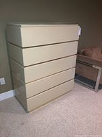Straight front view of the beige vintage Bassett dresser showing all five drawers closed on a light-colored carpet.