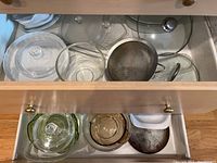 Top drawer with clear glass bowls, pie plates, casserole dishes and a metal saucepan with lid.