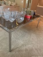 Photo of the rectangular smoked glass dining table with silver-toned metal frame and legs, tabletop holding glassware