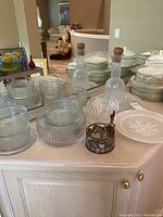 Overview photo showing Dansk glassware set including decanters, ribbed bowls, platters, and dinnerware stacks.