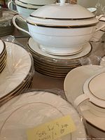 Close-up of a soup tureen with lid and handles on stacked plates, all with gold trim.