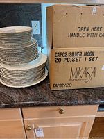 Stack of more than 50 Mikasa Silver Moon dishes next to original box marked 20 pc set bone china.