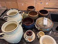 Full lot overview showing all 12 assorted ceramic pieces including jars, pots, casserole, pitcher, and smaller vessels