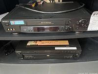 Front view of Sony VCR (top) and Sony DVD/CD player (bottom) showing model details and front panels with controls and connection ports, including RCA inputs on VCR.
