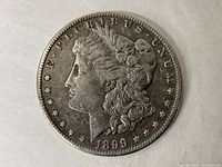 Obverse view of 1899 silver Morgan Dollar coin showing Lady Liberty profile, date 1899, and stars around edge.