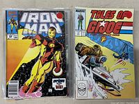 Two comics side by side in plastic sleeves, Iron Man and Tales of GI Joe from 1980s Marvel series
