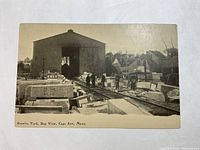 Front view of the antique postcard showing granite blocks and a large building labeled Granite Yard, Bay View, Cape Ann, Mass.