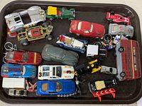 Top view photo showing the full assortment of 17 assorted antique and vintage toy cars and models on a tray.