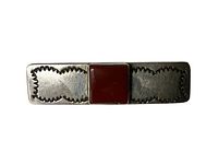 Front view of rectangular sterling silver pin with central square carnelian stone and etched geometric designs on either side.