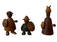Three wooden Viking figurines standing side by side, showcasing varying shapes and sizes made from teak wood.