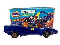 Front and side view of the 14-inch blue Batmobile toy with original colorful box behind it showing the Super Powers Collection and The Caped Crusaders graphics.