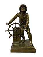 Front view of bronze coated fisherman statue at ship's wheel showing figure's pose and base