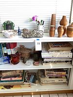 Full shelf showing cookbooks stacked, glass sculptures, woven baskets, and bowls on display