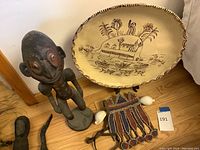 Photo of the full set including the large ceramic plate, carved wooden statue, beaded fabric piece, and shells.