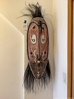 Full front view of carved wooden mask hung on wall