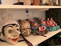 Overview of all items on shelf including two masks, animal head mask, sculpture and box