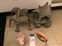 Full view of the metal elephant cart sculpture with two pig figurines placed in front