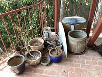 Group of assorted plant pots on brick patio, various sizes and materials