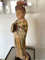 Front view of ceramic figurine showing full-body sancai glaze and wood base
