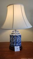 Front view of a blue and white porcelain table lamp on wooden base with fabric shade