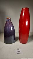 Two ceramic vases side by side shown on white surface, red vase taller and slender, blue-purple vase shorter and wider