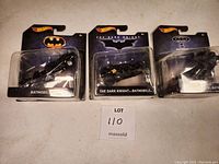 Three sealed Hotwheels Batman collectible cars in original packaging, showing front view of package and cars.