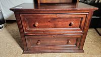 Front view of the wooden 2-drawer horizontal file cabinet with visible wear and round wooden knobs on drawers.